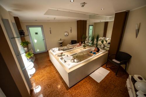 ein großes Bad mit einer Badewanne und einem großen Spiegel in der Unterkunft Hotel Seehof Haltern am See in Haltern