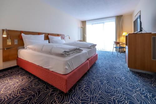 a hotel room with a large bed and a television at Hotel Seehof Haltern am See in Haltern