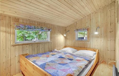 a bed in a wooden room with two windows at Awesome Home In Rdby With 3 Bedrooms And Wifi in Kramnitse