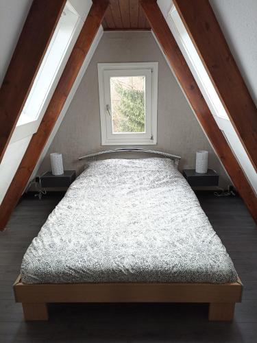 a bed in a attic with a window at Bungalow Sud-Harz Bleicherode onder in Bleicherode