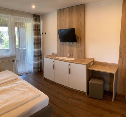 a room with a bed and a desk with a tv at Pension Hartmann in Sankt Kanzian