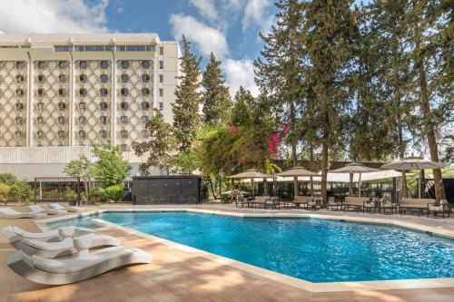 a swimming pool with chairs and a hotel at Golden Tulip El Mechtel in Tunis
