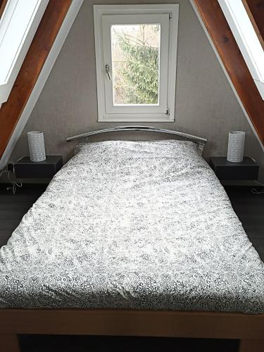 a bed in a room with a window at Bungalow Sud-Harz Bleicherode - boven in Bleicherode