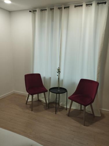 two chairs and a table in a room with white curtains at MiddleHouse in Braşov