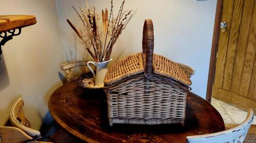 a table with a basket and a vase on it at The Orchards Guest Suite in Willand