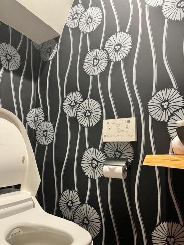 a bathroom with a toilet with dandelions on the wall at Yanaka Kotobuki Sou in Tokyo