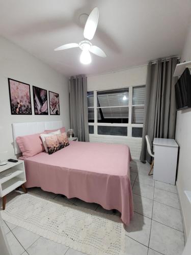 a bedroom with a pink bed and a window at Praia do Tombo in Guarujá