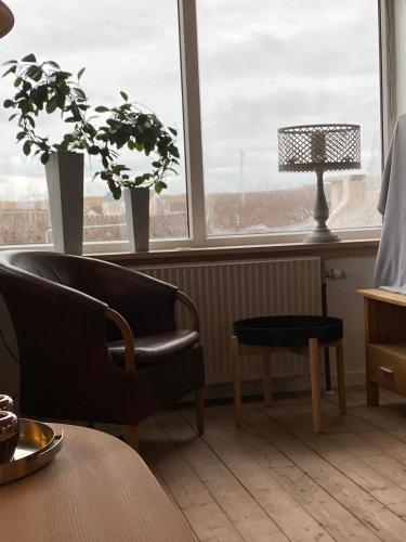 a living room with a chair and a table and a lamp at 200 m til havet - fri adgang til svømmehal in Thyborøn