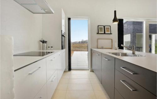 ロッケンにあるBeautiful Home In Lkken With 3 Bedrooms, Sauna And Wifiの白いキャビネットと大きな窓付きのキッチン