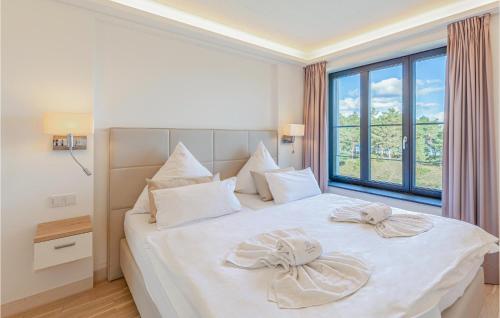 ein Schlafzimmer mit einem weißen Bett mit zwei Bögen darauf in der Unterkunft Sunny in Binz