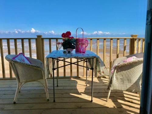 - une table et deux chaises sur une terrasse avec vue sur la plage dans l'établissement Stylish Boatwright Cottage moments from beach by Whitstable-Holidays, à Whitstable