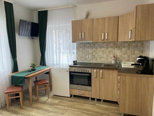 a kitchen with wooden cabinets and a sink and a table at Island apartman in Odorheiu Secuiesc