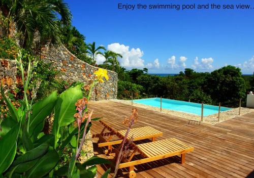 una terraza de madera con un banco y una piscina en Propiedad de alto standing con vista al mar, piscina, tenis, hasta 12 personas en Las Terrenas