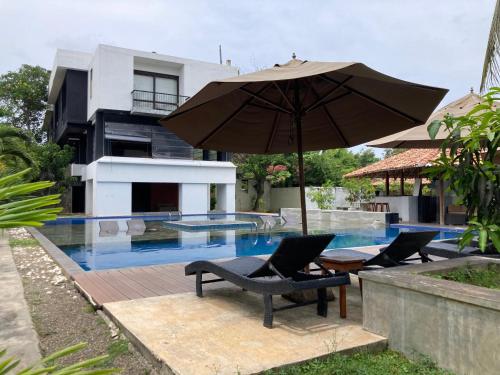 an umbrella and two chairs next to a swimming pool at Handagedara Resort & Spa in Mirissa