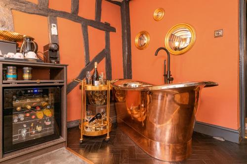 uma banheira de cobre num quarto com uma parede laranja em Funky Monk Hotel em Epping