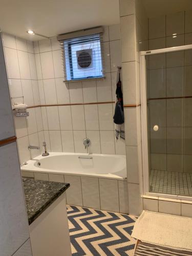 a bathroom with a tub and a shower with a window at Villa Paulina Family suite in Langebaan
