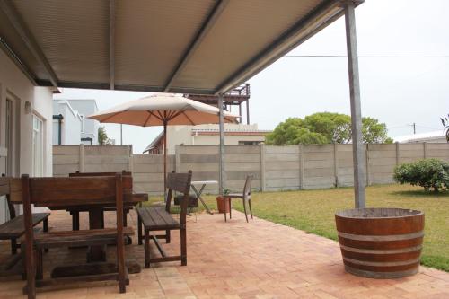 a patio with an umbrella and a table and chairs at Kusweg Suid 4 in Struisbaai