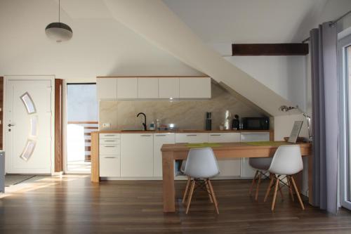 a kitchen with a wooden table and white cabinets at Apartament u Ewki in Rdzawka