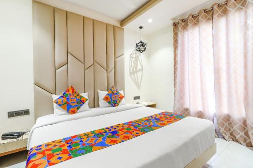 FabHotel Harriot في بوبال: غرفة نوم مع سرير كبير مع بطانية ملونة