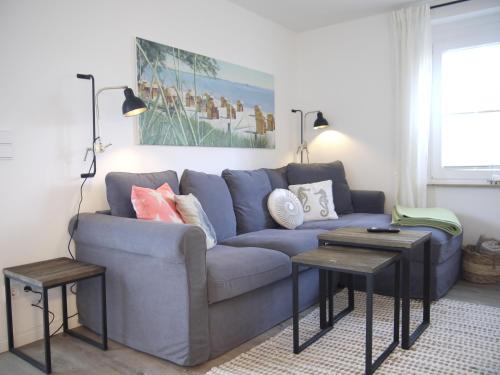 a living room with a blue couch and two tables at Ocean Hill in Scharbeutz