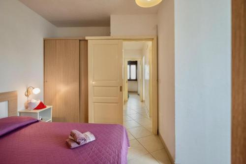 a bedroom with a purple bed and a hallway at Villette Ninfee in Marina di Mancaversa