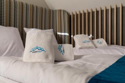 two white beds with towels on top of them at Green Park Resort A25 -z dostępem do basenu, sauny, jacuzzi, siłowni in Szklarska Poręba