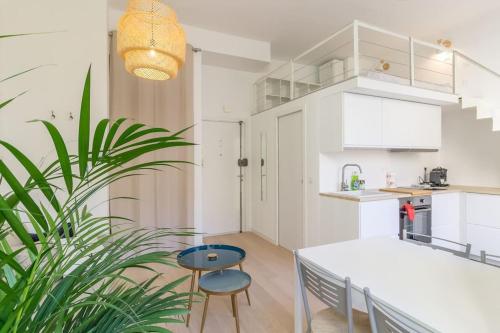 une cuisine avec des placards blancs, une table et une plante dans l'établissement Charming studio mezzanine w/ large terrace - Nice, à Nice