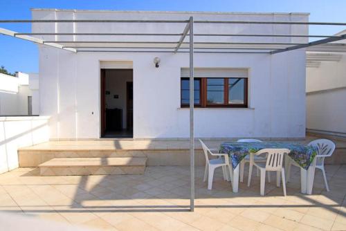 a patio with a table and chairs and a house at Villette Ninfee in Marina di Mancaversa