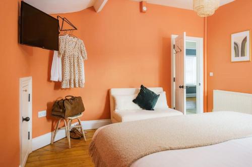 a bedroom with orange walls and a bed and a couch at Loft Fawr in Tregaron