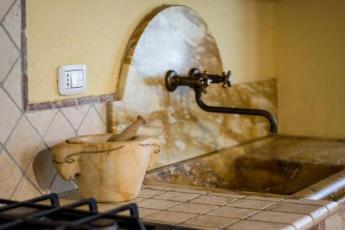 a bathroom with a sink and a toilet with a faucet at Casetta della Pina in Monticiano