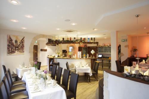 a restaurant with white tables and chairs and a bar at Hotel-Pension Am Schwanenteich in Lutherstadt Wittenberg