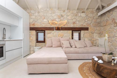 a living room with a couch and a stone wall at Pure Amber Suite Elani in Siviri
