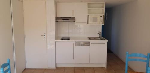 uma pequena cozinha com armários brancos e um lavatório em Appartement-Marina climatisé 4 couchages avec Piscine em Saint-Cyprien-Plage