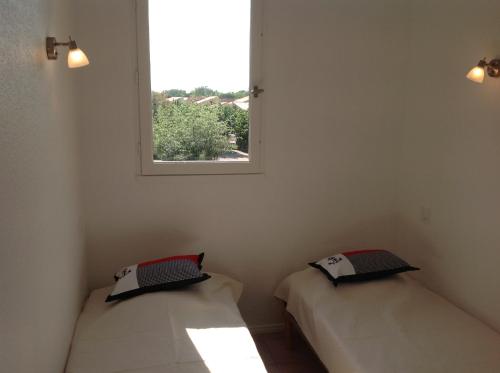 deux lits dans une chambre avec une fenêtre dans l'établissement Appartement-Marina climatisé 4 couchages avec Piscine, à Saint Cyprien Plage