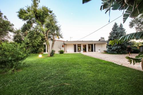 uma casa com um relvado verde em frente em Villa con parco e piscina em San Michele Salentino
