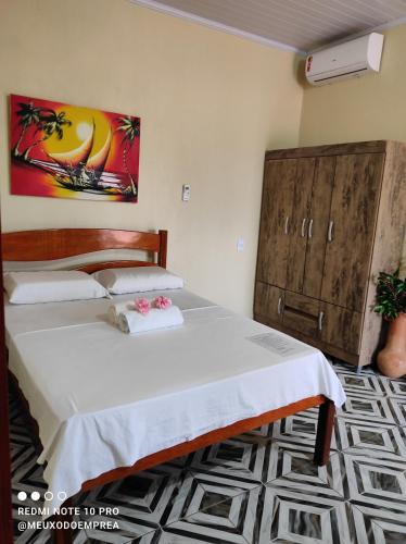 a bedroom with two beds and a painting on the wall at Pousada Meu Xodó in Prea