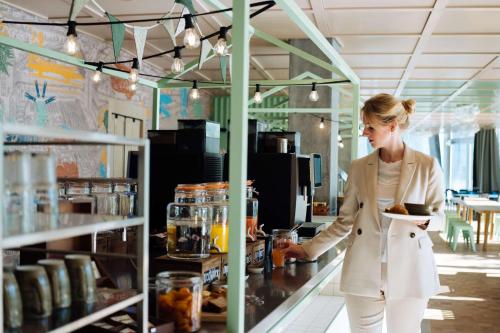 a woman standing in a kitchen preparing food at Hyatt Place Zurich Airport the Circle in Kloten