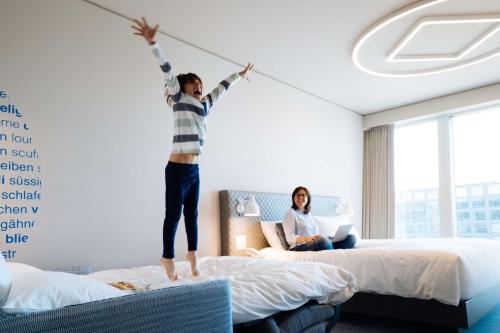a young boy jumping on a bed in a hotel room at Hyatt Place Zurich Airport the Circle in Kloten