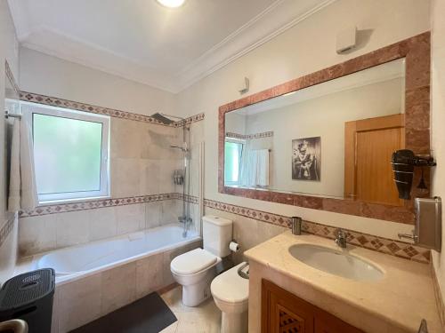 a bathroom with a tub and a toilet and a sink at Sea and Sun 4 You - Palheiro Village in Funchal
