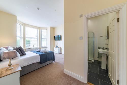 a bedroom with a bed and a bathroom with a shower at Greyfriars in Clacton-on-Sea