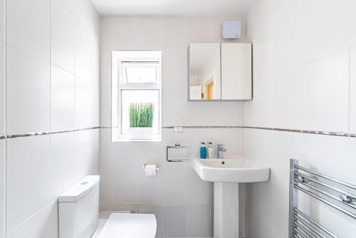 a white bathroom with a toilet and a sink at Greyfriars in Clacton-on-Sea