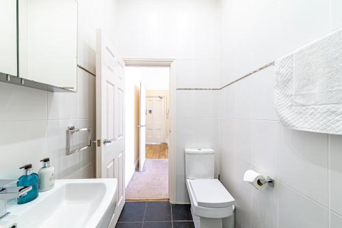 a white bathroom with a sink and a toilet at Greyfriars in Clacton-on-Sea