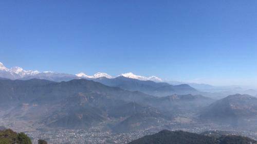 a view of a mountain valley with snow capped mountains at Hilltop Restaurant and guesthouse in Pokhara