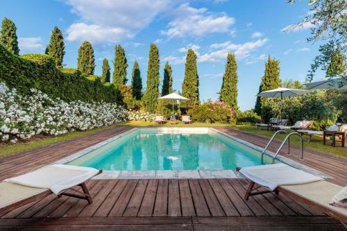una piscina en un jardín con terraza de madera en VILLA IL TINAIO Romantic Secluded Farmhouse with Private Pool, en Valgiano