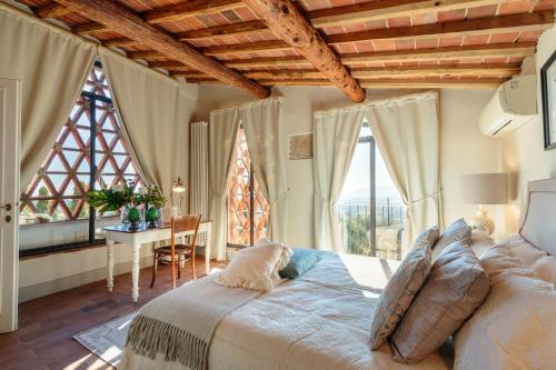 1 dormitorio con cama, mesa y ventanas en VILLA IL TINAIO Romantic Secluded Farmhouse with Private Pool, en Valgiano