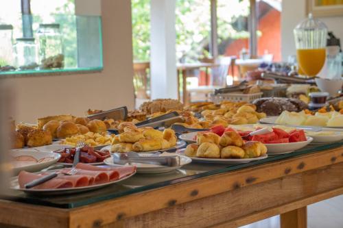 um buffet repleto de diferentes tipos de produtos de pastelaria e frutas em VELINN Hotel Ninho do Falcão em Monte Verde