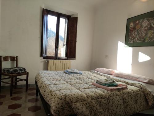 a bedroom with a bed and a window and a chair at Il ristoro del viandante in Licciana Nardi