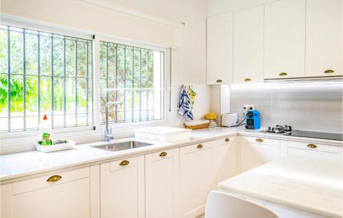 uma cozinha com armários brancos, um lavatório e janelas em Awesome Home In Marbella With Wifi em Marbella