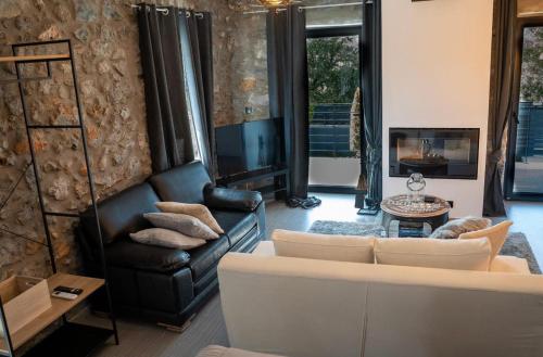 a living room with a leather couch and a tv at Triantos Guesthome Studio in Tripolis