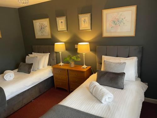 um quarto com duas camas e duas lâmpadas sobre uma mesa em Broadlands em Bourton on the Water